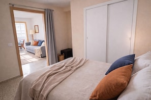 Un dormitorio con cama, armario y vista a una sala de estar.