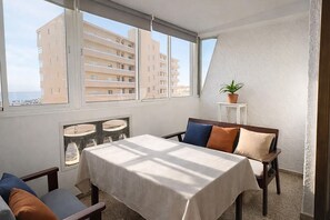 Quarto com cama, mesa e janela com vista para edifícios.