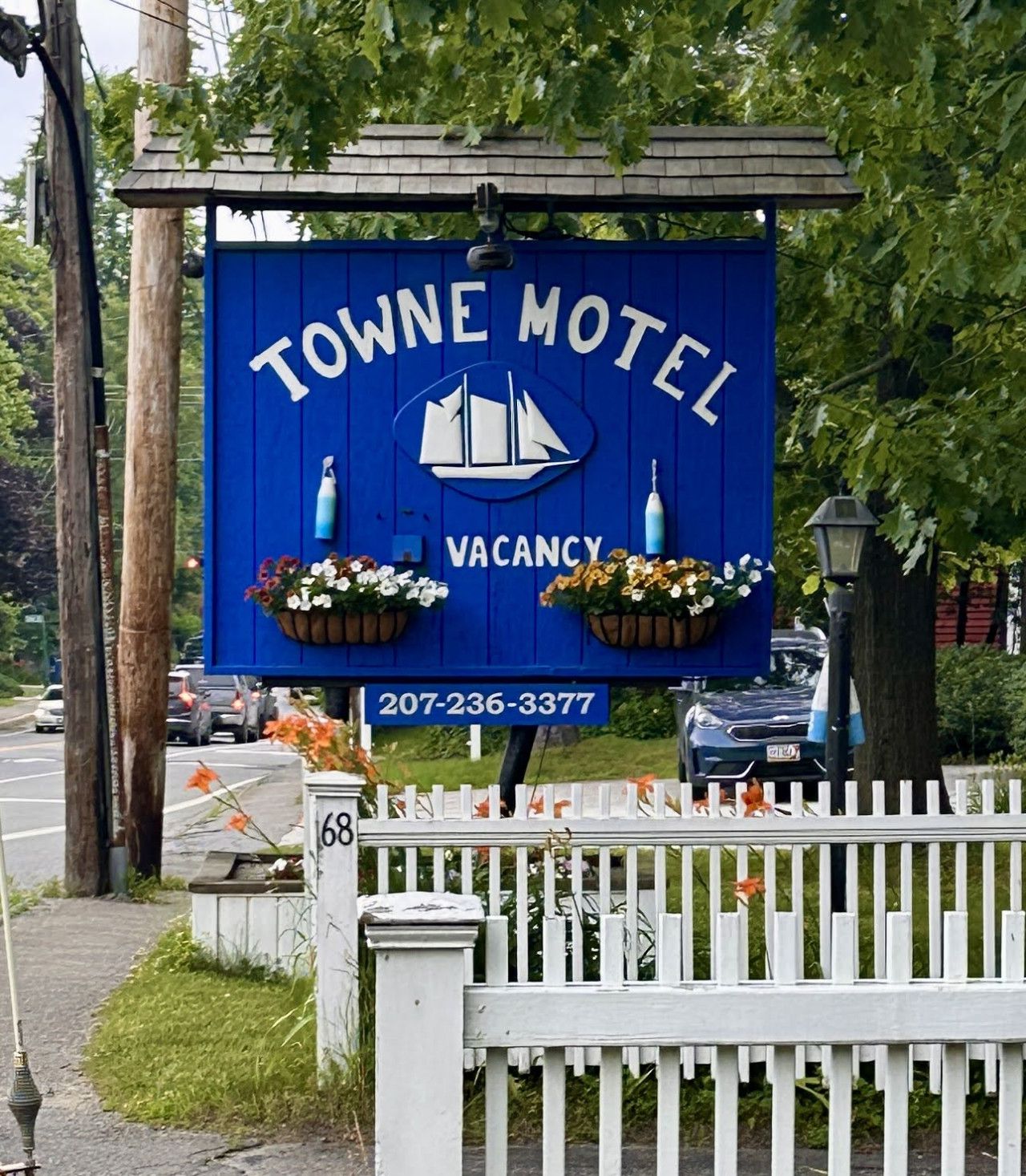 Cartel azul del Motel Towne con logotipo de velero, indicando disponibilidad y un número de contacto.