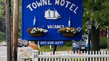 Cartel azul del Motel Towne con logotipo de velero, indicando disponibilidad y un número de contacto.