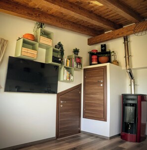 Una habitación con techo de madera, televisor de pantalla plana, un armario de madera y una chimenea roja.