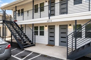 Un bâtiment à deux étages avec un escalier, portant le numéro 6813, et une voiture garée devant.
