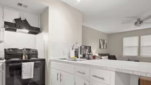 Una cocina moderna con armarios blancos, una estufa negra y un lavamanos de acero inoxidable.