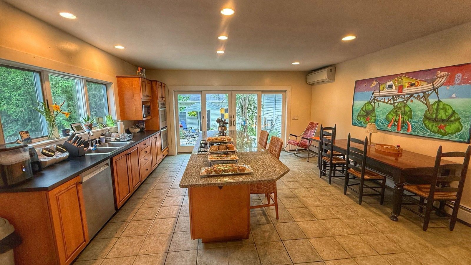 Cocina amplia con una isla central, zona de comedor con una mesa grande y vistas a través de puertas de cristal.