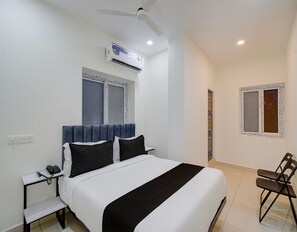 Ein Hotelzimmer mit einem Bett, einem Schreibtisch, einem Sessel, einer Klimaanlage und einem Fenster.