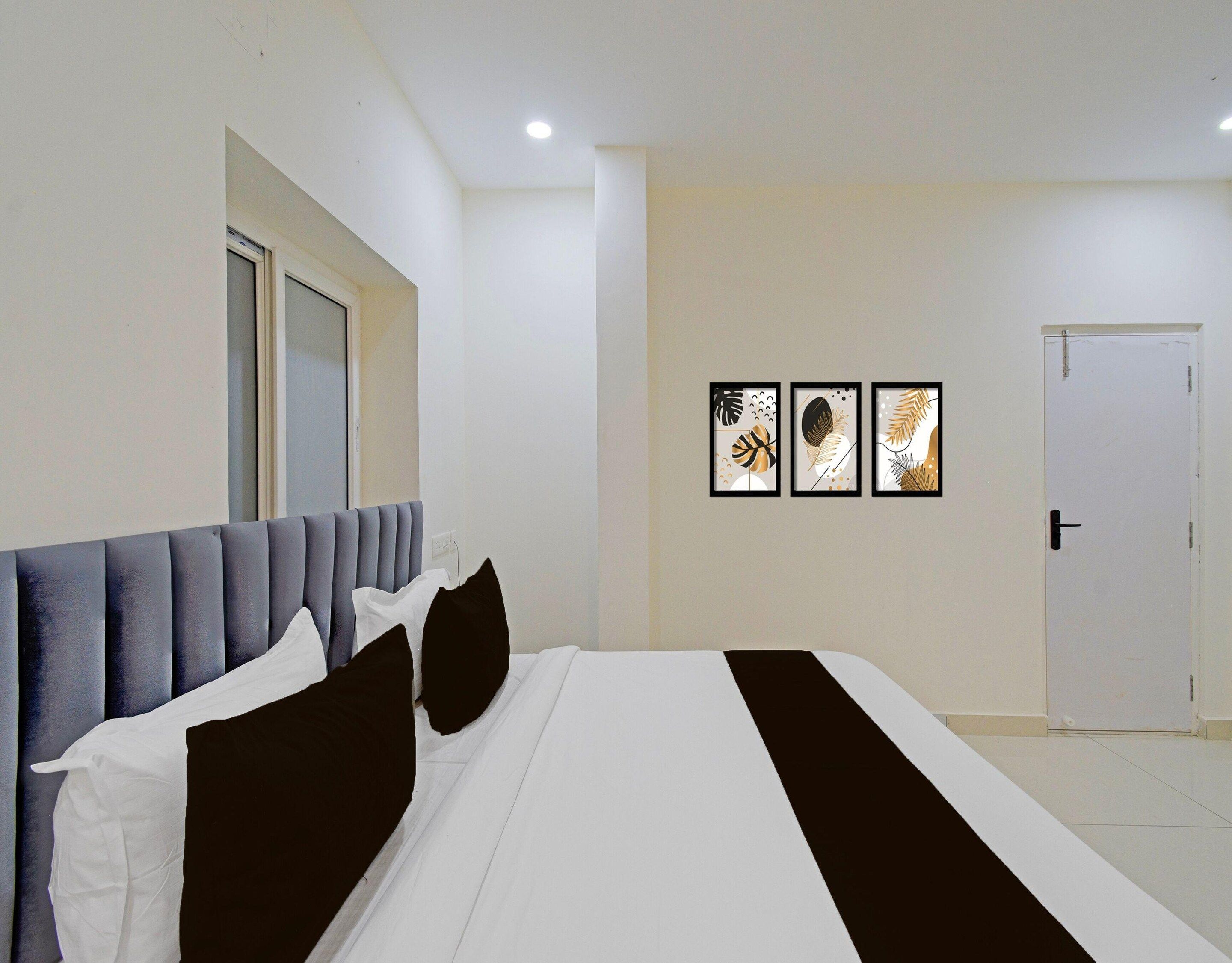 A hotel room with a bed, a door, and three framed artworks on the wall.