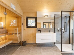 A modern bathroom with a wooden interior, a glass shower enclosure, and a large mirror. - Superior Chalet #23 With Sauna & Hot Tub (Stadl-Predlitz)