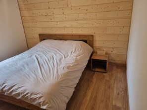 A single bed with a wooden headboard in a room with wooden walls and flooring. - L'Écrin d'Orelle Apartment – 2 Bedrooms, Mountain Views, Near Gondola (Orelle)