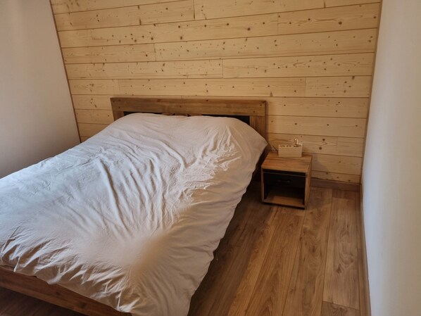 Een eenpersoonsbed met een houten hoofdeinde in een kamer met houten wanden en vloer.