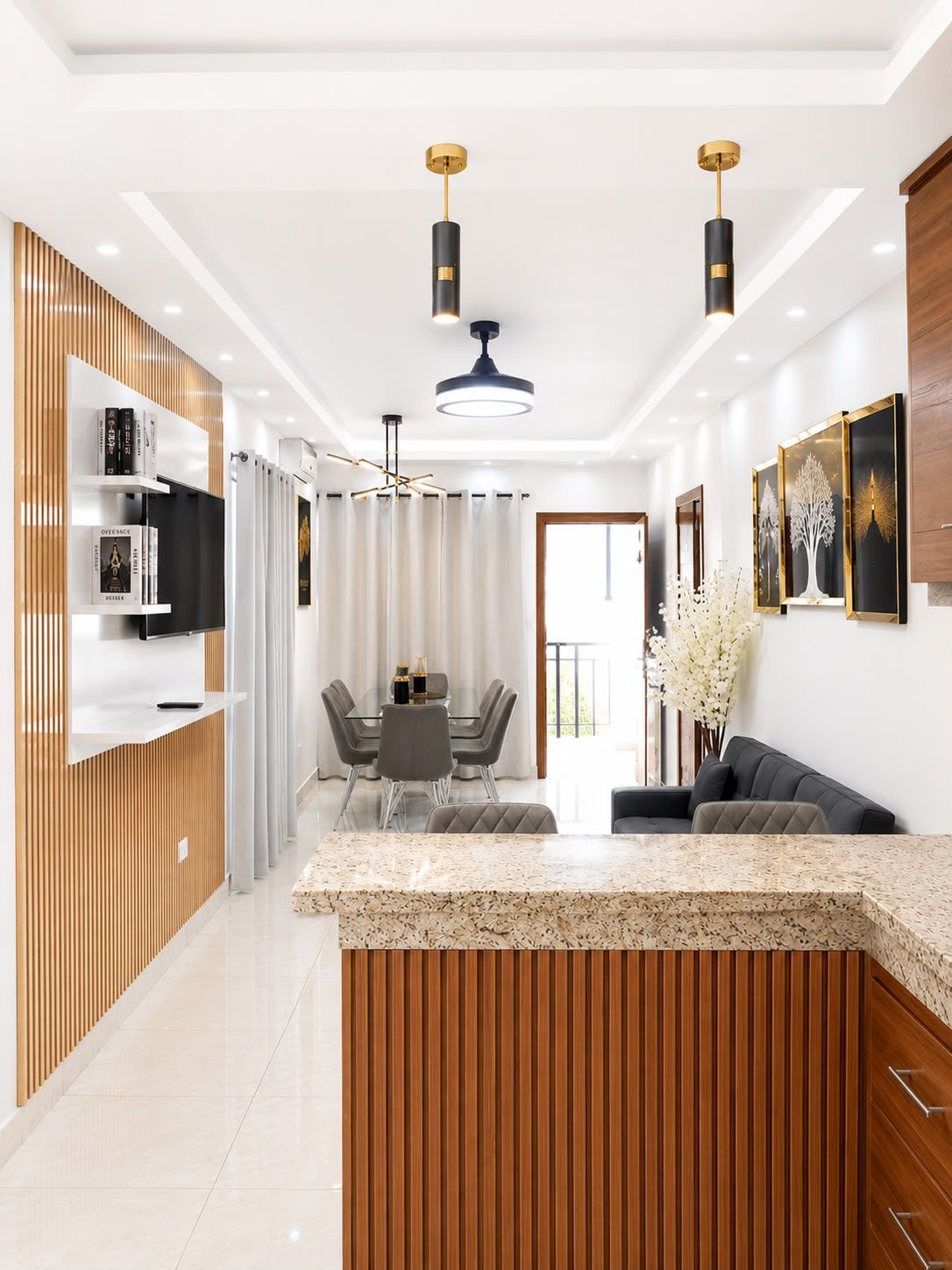 Une cuisine moderne dotée d’un îlot central, de luminaires suspendus et d’un coin repas avec une table et des chaises.