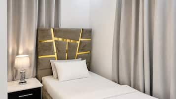 Un dormitorio moderno con cama, mesita de noche, lámpara y cortinas.