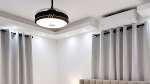 A modern bedroom with a large bed, a bedside table with a lamp, and an air conditioning unit. - residencial los garcia la romana  (La Romana)