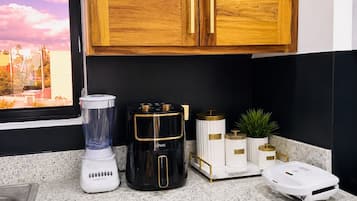 Una cocina con encimera de granito, licuadora, cafetera y balanza.