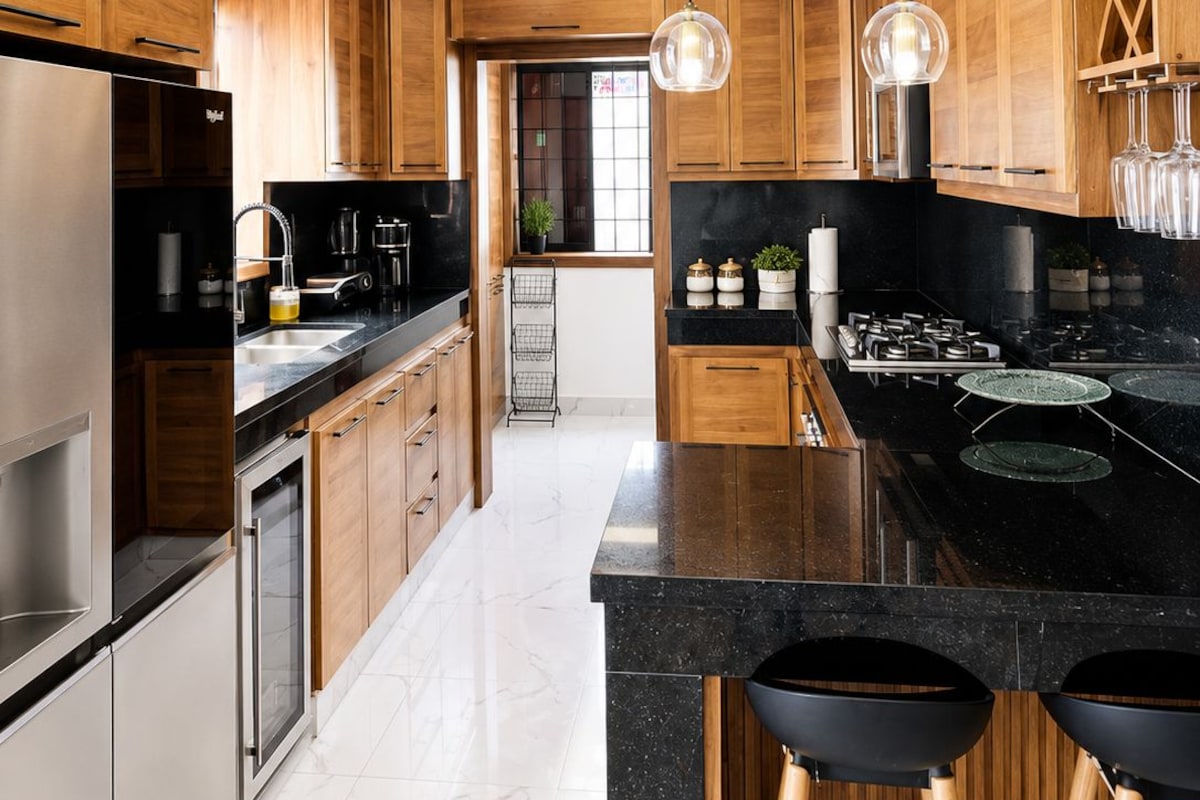 Una cocina moderna con armarios de madera, encimera negra y una isla central con taburetes.