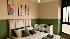 Un dormitorio con cama, mesita de noche y cuna.