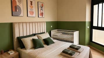 Quarto com cama, mesa de cabeceira e berço.