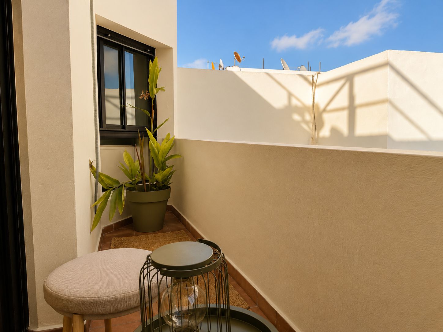 Un balcon agrémenté de plantes en pot, une petite table ronde et une fenêtre.