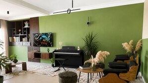 Un salón con piano, sofá, mesa de centro y varias plantas.