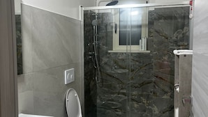 Ein modernes Badezimmer mit einer gläsernen Dusche, einer Toilette und einem Waschbecken.