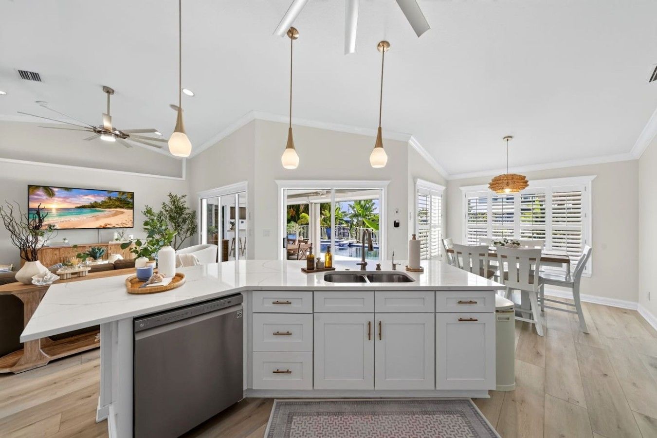 A spacious kitchen with a large island, white cabinetry, and pendant lighting.