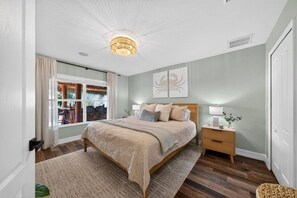 A bedroom with a bed, bedside tables, a window with curtains, and a ceiling light fixture. - Matlacha Isles Waterfront - Pool, Spa & Tiki Bar (Matlacha Isles-Matlacha Shores)