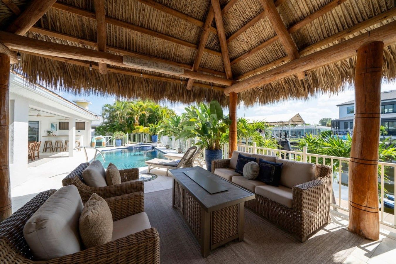 Un espacio de estar techado al aire libre con mobiliario de mimbre, una piscina y vistas del paisaje circundante.