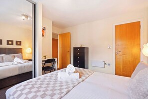 A hotel room with a bed, a desk, a wardrobe, and a mirror. - Stylish City Centre Living (Birmingham)