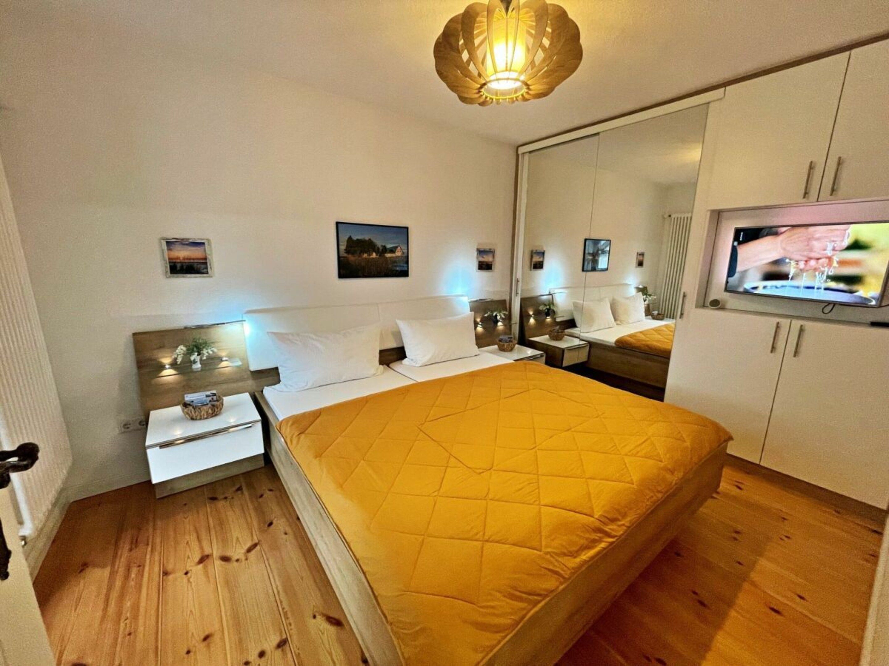Une chambre d’hôtel avec un lit, des tables de chevet, une télévision et un miroir.