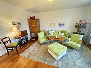 A living room with a sofa, armchairs, a coffee table, a wooden cabinet, a sewing machine, and a lamp. - Holiday Home Anna (Benz)