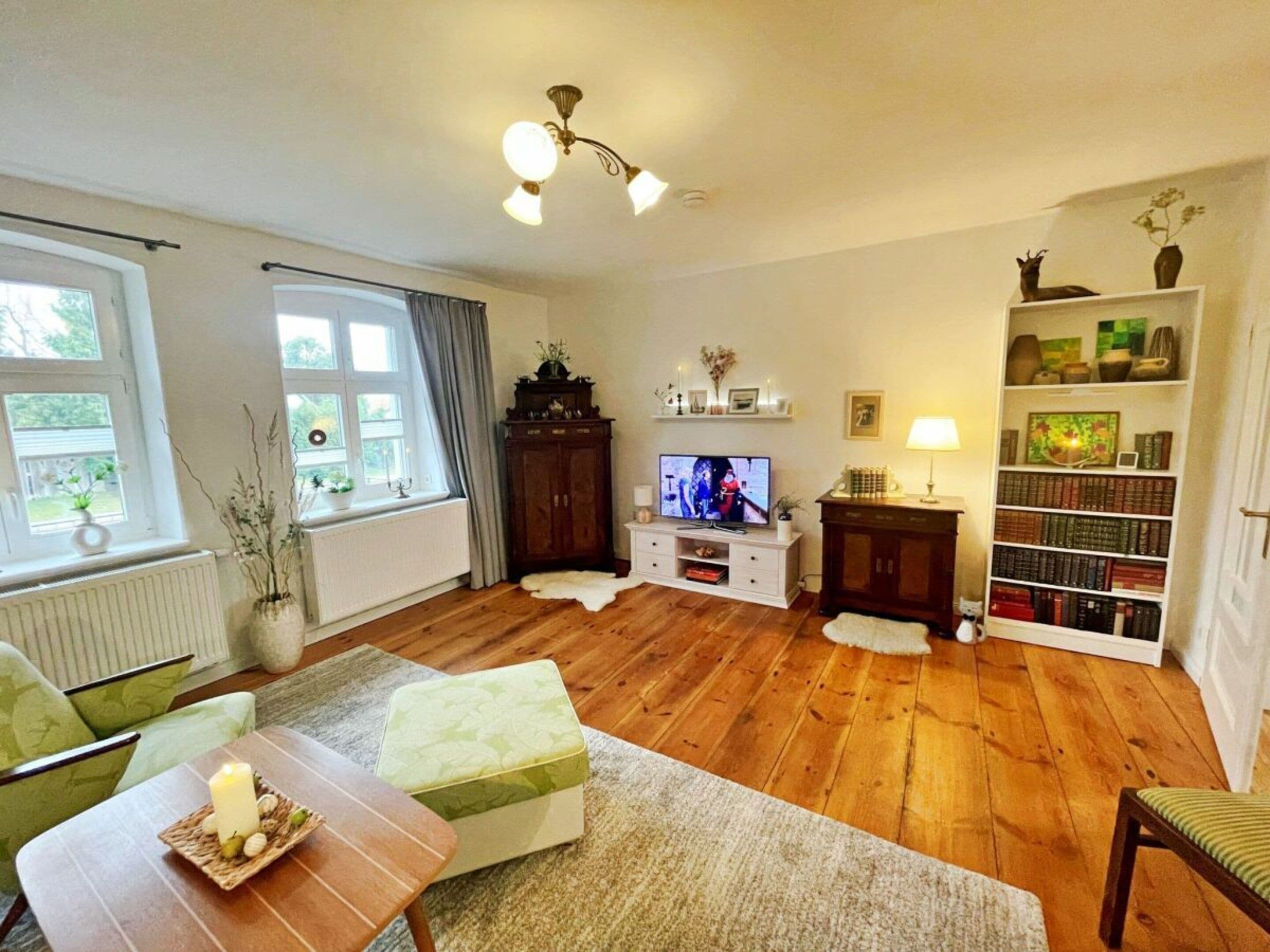 Una sala de estar con televisor, estanterías, chimenea y ventana con cortinas.