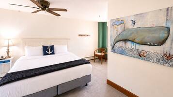A bedroom with a bed, a ceiling fan, a chair, and a wall painting.