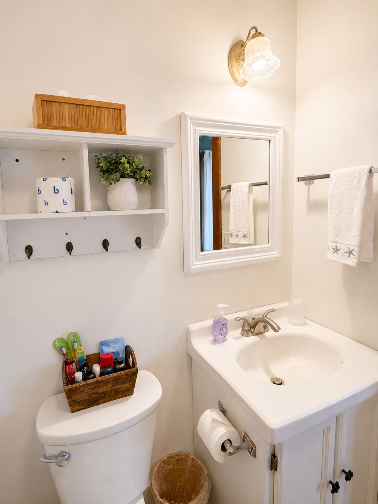 Une salle de bain équipée de toilettes, d’un lavabo et d’étagères où sont rangés les articles de toilette.