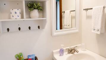 Une salle de bain équipée de toilettes, d’un lavabo et d’étagères où sont rangés les articles de toilette.