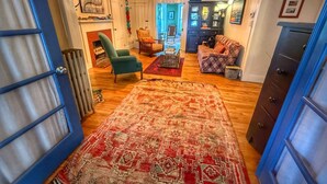 Ein gemütliches Wohnzimmer mit Kamin, einem gemusterten Teppich und einer blauen Tür.