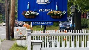 Ein blaues Schild des Towne Motel mit einem Segelboot-Logo, das eine freie Unterkunft anzeigt, und einer Kontaktnummer.