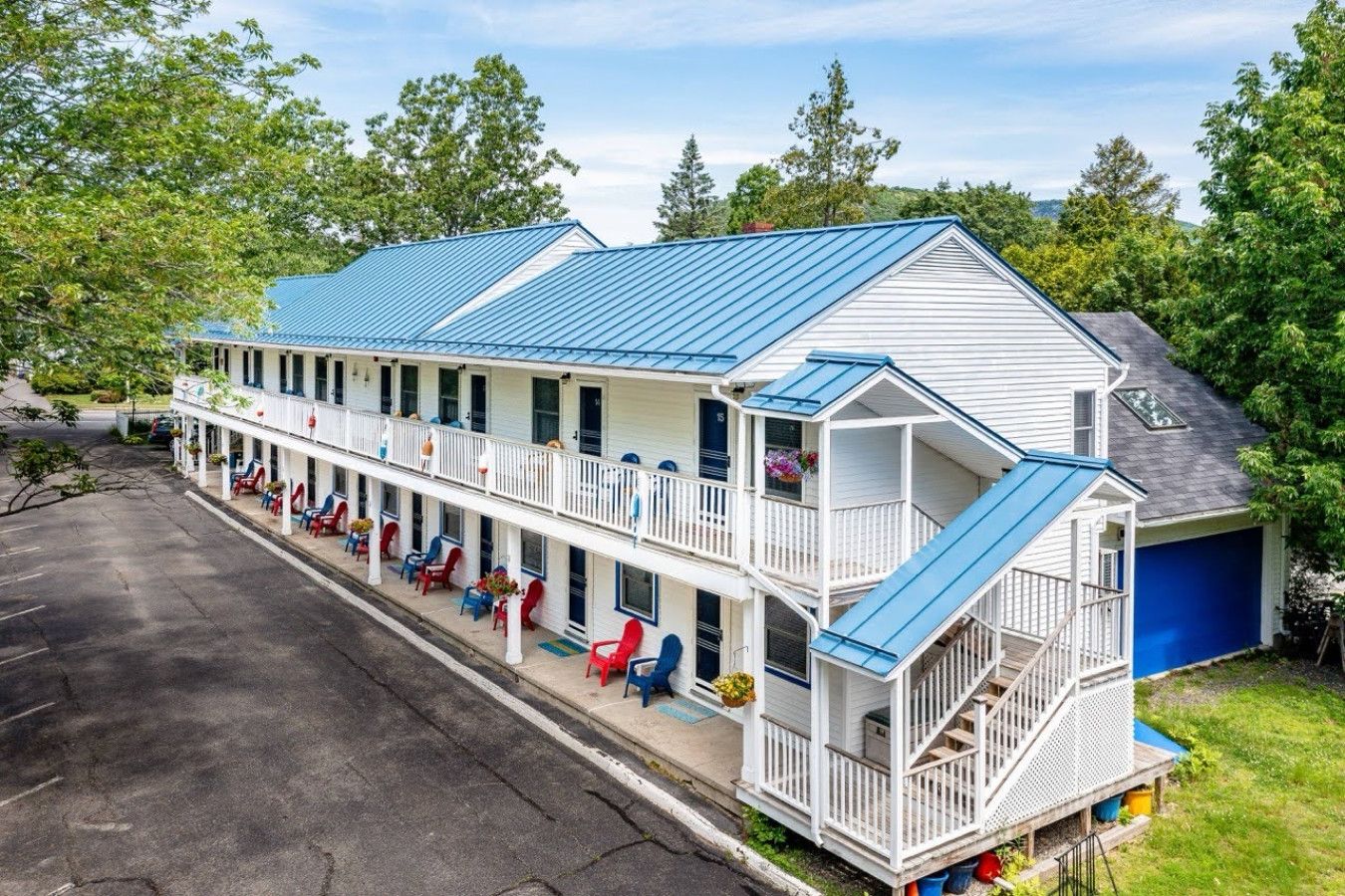 Ein zweistöckiges Motel mit blauem Dach, mehreren Balkonen und Außenbereichen zum Sitzen.