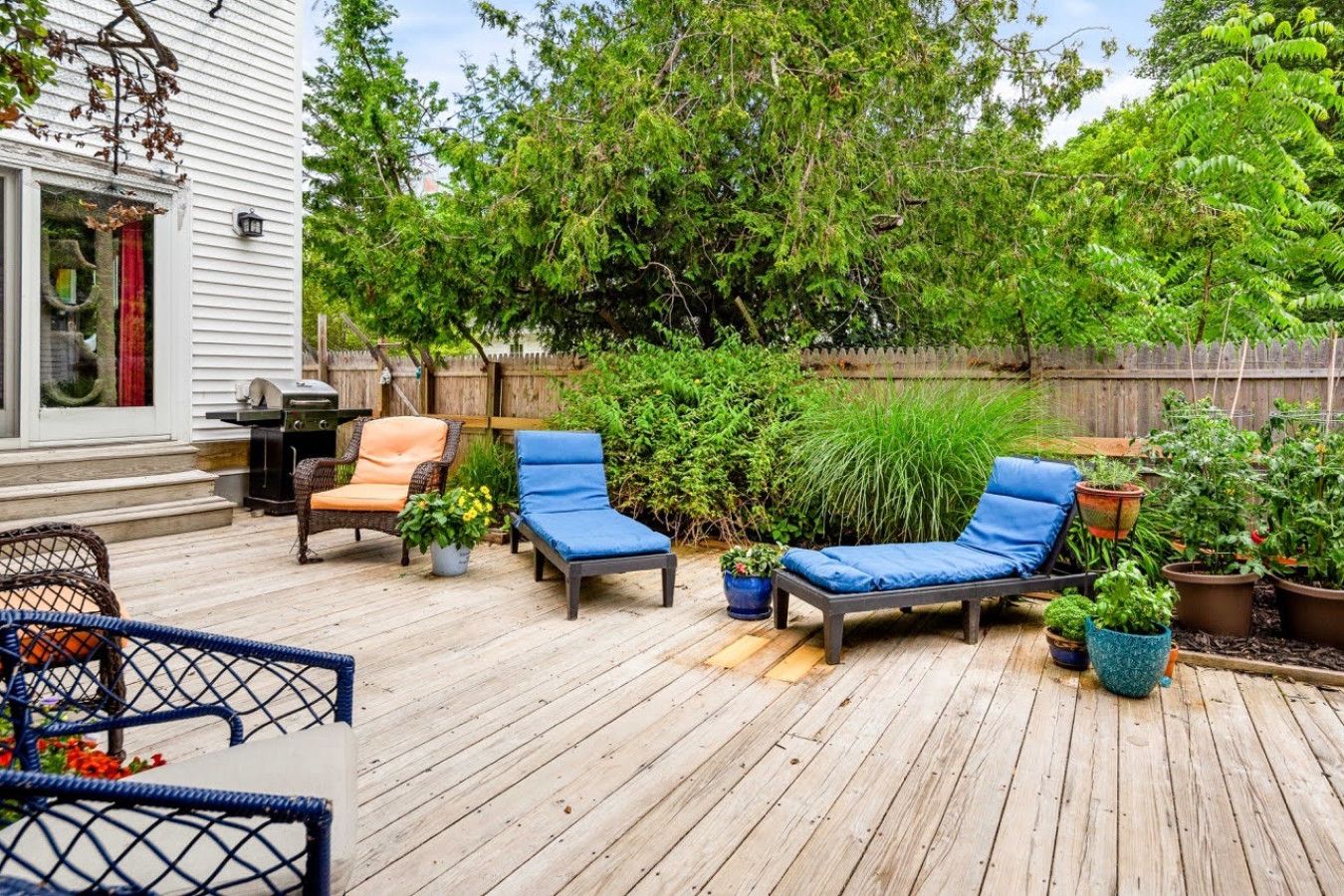 Una terraza de madera con sillones de descanso y una parrilla.