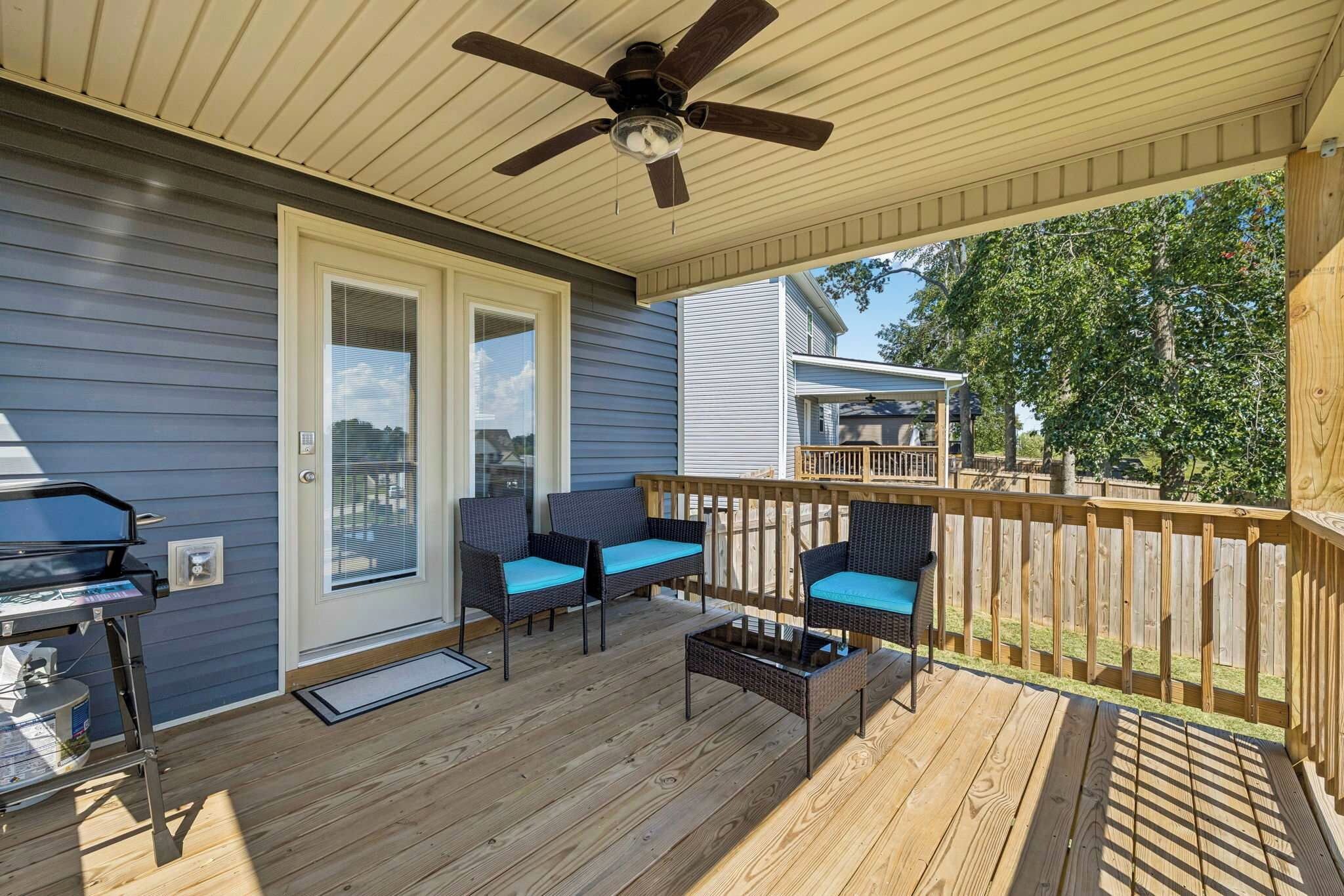 Una terrazza coperta con due sedie, un tavolo, una ventola a soffitto e un barbecue.