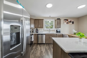 Una cocina moderna con electrodomésticos de acero inoxidable, armarios de madera y una isla central.