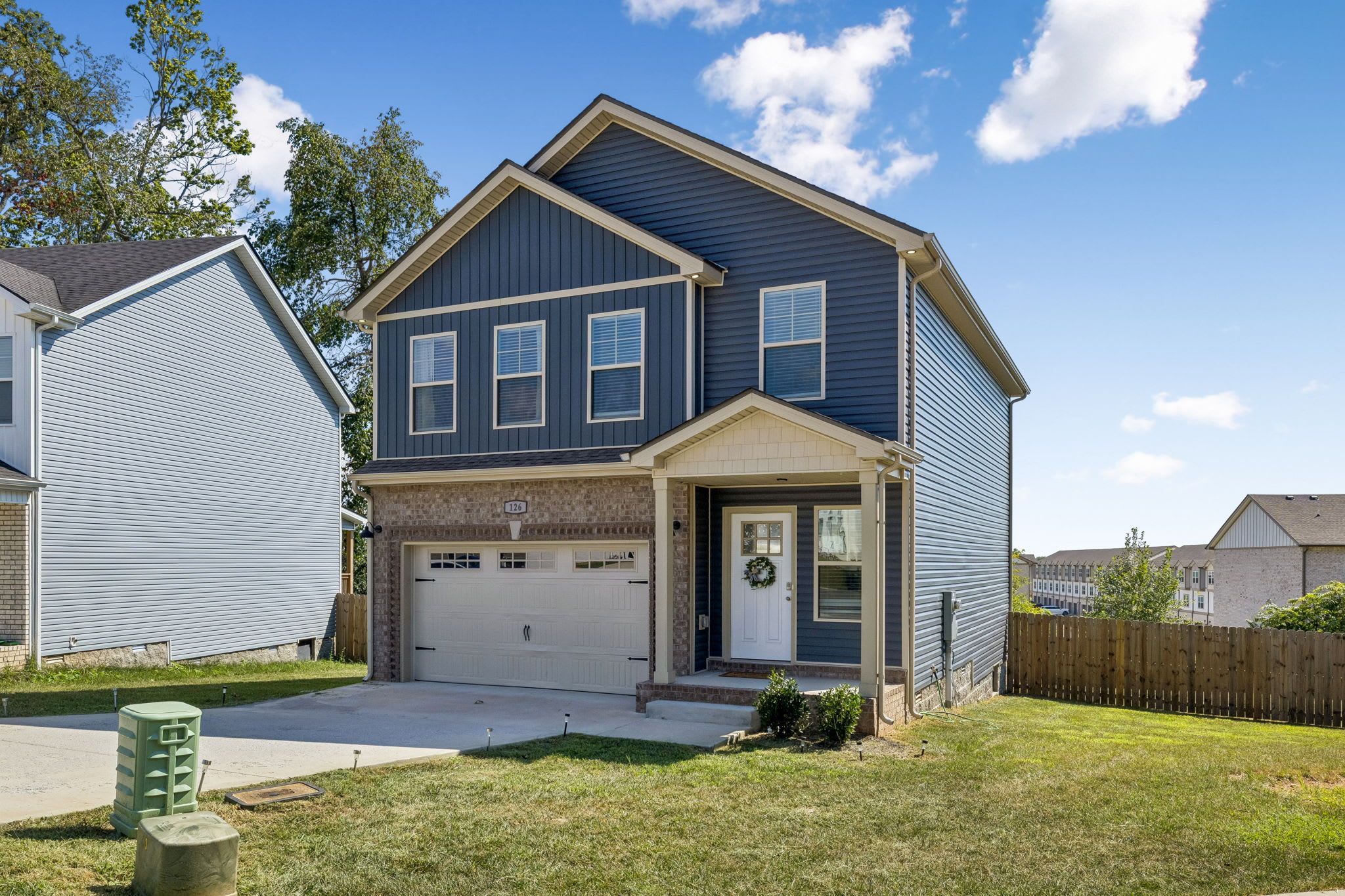 A two-story residential house with a garage, a front porch, and a well-maintained lawn.
