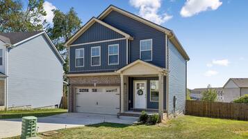A two-story residential house with a garage, a front porch, and a well-maintained lawn.