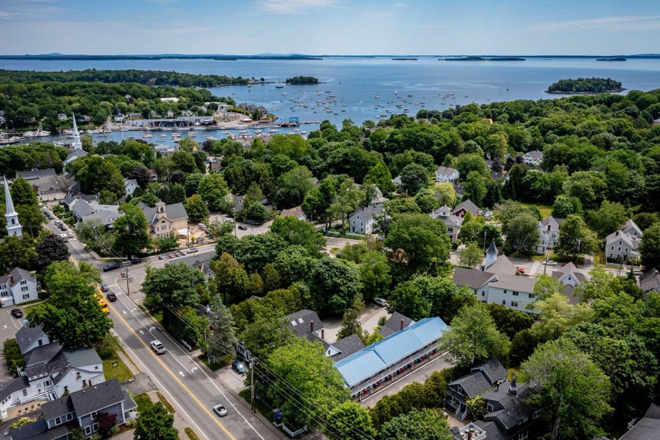 An aerial view of a coastal town with residential areas, a church, and a marina with boats.
