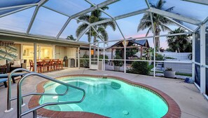 A swimming pool with a glass enclosure, surrounded by a patio area with outdoor furniture. - Water Views | Beach | Pool | Paddle Boards (Bradenton)