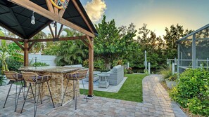 An outdoor patio with a pergola, a dining table with chairs, and a seating area with a sofa and side tables. - Water Views | Beach | Pool | Paddle Boards (Bradenton)