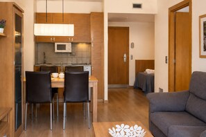 A compact living space with a kitchenette, a dining area with chairs, a sofa, and a small table. - Superior Family Coastal Escape for 3 People (Pals)