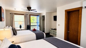 A hotel room with two beds, a ceiling fan, a window with curtains, a wooden door, and a dresser. - Towne Motel Camben Room #12 (Camden)