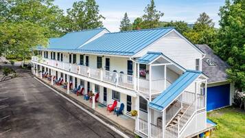 A two-story motel with a blue roof, multiple balconies, and outdoor seating areas.