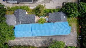Eine Luftaufnahme eines Gebäudes mit blauem Dach, umgeben von Bäumen und einem Parkplatz.