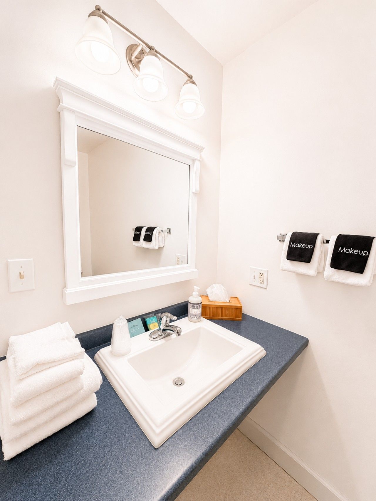 Une salle de bain avec un lavabo blanc, un miroir et un porte-serviettes avec des serviettes.