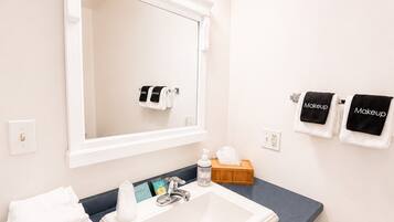 Une salle de bain avec un lavabo blanc, un miroir et un porte-serviettes avec des serviettes.